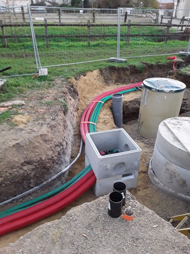 Regard de raccordement en béton avec fourreaux rouges et verts — chantier VRD